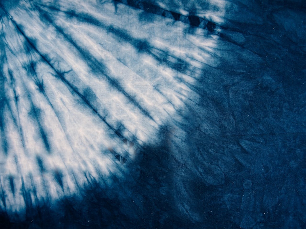Radiant indigo tie-dye pattern with soft lighting creating a dynamic abstract texture.