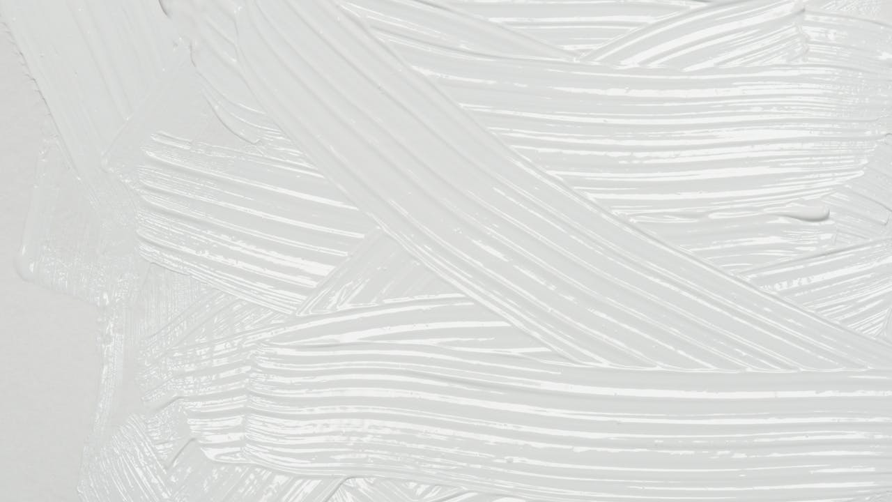 Close-up of white paint texture with brushstrokes creating an artistic background.